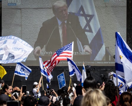 Crowds wave Israeli flags in front of large-screen showing Donald Trump’s speech
