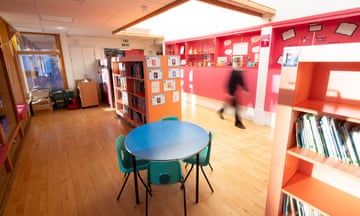 A bright primary school room with a small table and bookcases with books.