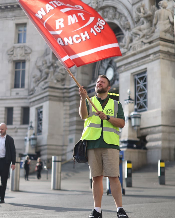 A member of the Rail, Maritime and Transport union (RMT) outside Waterloo train station.