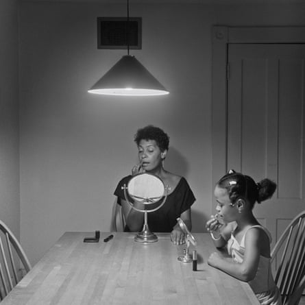 A woman and her daughter put on makeup at a kitchen table.