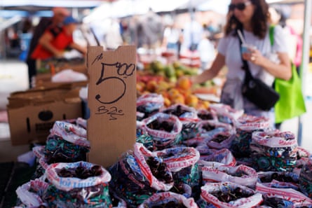 bags of cherries on a table and a sign that reads ‘$5’ at a farmers market