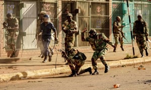A soldier fires shots towards demonstrators.