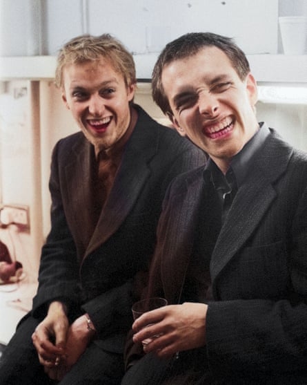 They sit together, grinning maniacally, with drinks and pink-stained teeth