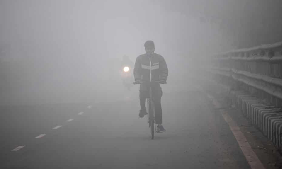 A man rides a bicycle along a street in heavy smog in Delhi.