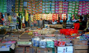 A stall with dozens of sachets hanging from clips and boxes of other consumer goods