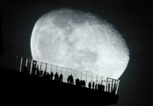 New York City, US: a waning moon rises behind people standing on the Edge outdoor observation deck at Hudson Yards