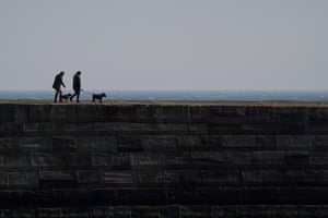 People walk their dogs along the seawall in Whitby