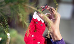 person dressing the christmas tree with a handmade decoration red stocking