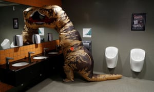 A visitor to London Comic Con wearing a T-Rex costume uses the lavatory