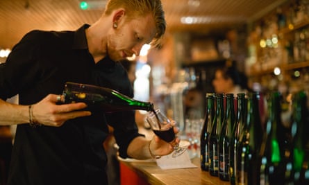 Hipster barman pours dark beer from bottle, North Bar, Leeds