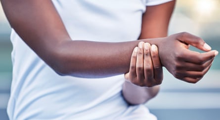 A black woman holds her wrist.