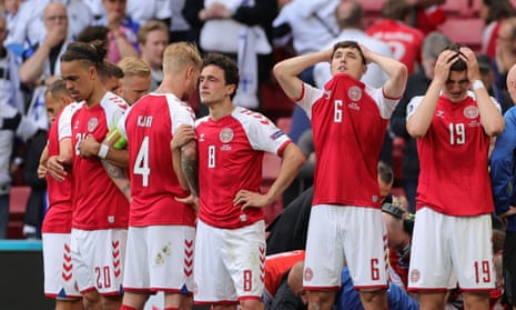 Danish footballers form a shield around Christian Eriksen as he is being treated on the pitch