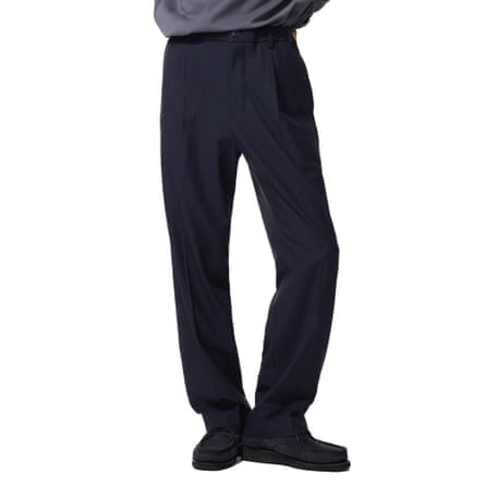 The model wears a pair of loose dark navy trousers and black shoes.
