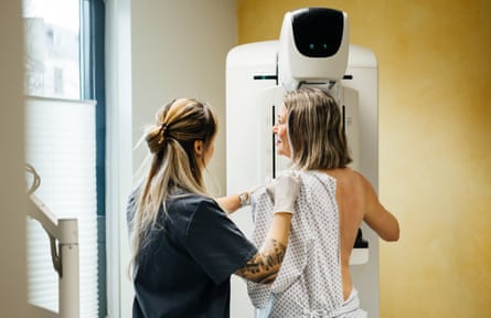 A healthcare professional helps a patient into position for a mammogram examination.