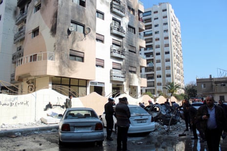 People gather near a damaged building in the Kafr Sousa district, Damascus, Syria.