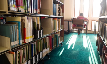 Rear view of a student sitting at a desk studying in a university library