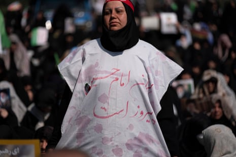 An Iranian worshipper wearing a shroud, alongside a Persian script that reads, ‘‘Imam Hussein’s Iran is victor,’’ stands at Imam Khomeini Grand Mosque before participating in Tehran’s Friday prayers in Tehran, Iran, on March 6, 2026.