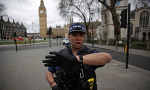 An armed police officer gestures as he stands guard in Parliament Square