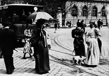 Women strolling along a street while a tram passes by in Vienna, 1892.