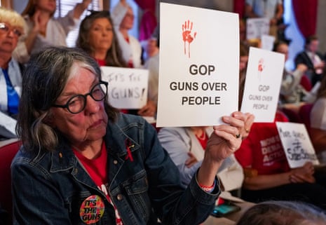 A person holds a sign that reads 'GOP guns over people'