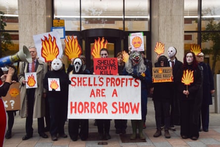 Climate activists hold banner that says ‘Shell’s profits are a horror show’ while wearing Scream masks and wearing black
