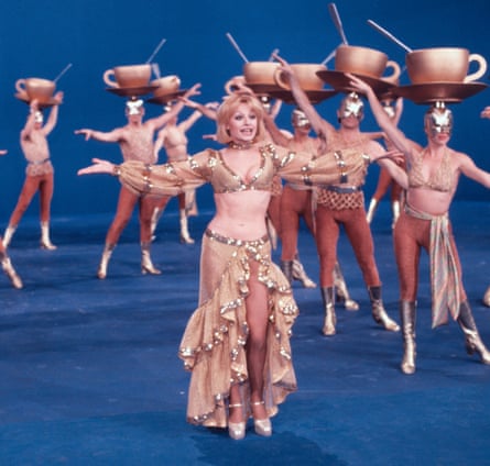 Raffaella Carrà dancing and singing wearing a belly top and skirt, surrounded by backup dancers with teacups and saucers on their heads.