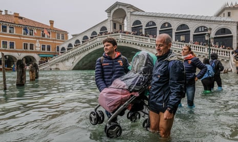 tourist carry a pushchair through flooded streets