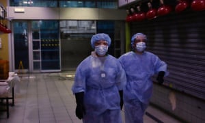 Janitors dressed in protective gear walk through an empty arcade in Hong Kong, 20 July 2020.
