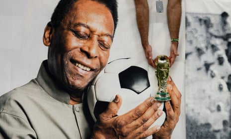A Brazil fan holds a replica World Cup trophy in front of a banner of Pelé at the Qatar World Cup.