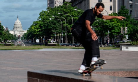 A man practices his skateboard skills on Freedom Plaza with the US Congress Capitol in the background in Washington DC.