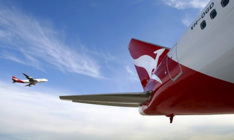 A Qantas jet flies past a parked plane