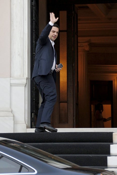 Greek Prime Minister Tsipras waves at reporters as he arrives at his office in Athens this afternoon.
