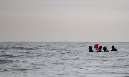 Migrants sit onboard a boat