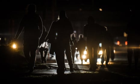 People walk on a dark street after the lights were switched off due to power cuts in Kyiv.