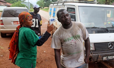 A health worker uses a thermometer to screen a man for Ebola in Guinea in 2014