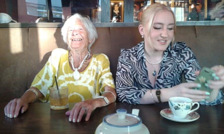 Pog, a woman in her 90s, sitting laughing with a drink in front of her