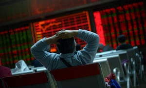 An investor looks at screens showing stock market movements at a securities company in Beijing