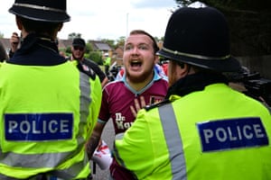 A demonstrator shouts as a police officer puts a hand on his chest to hold him back