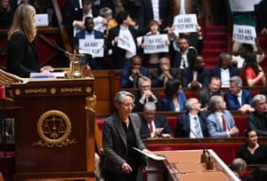 Paris MPs from the leftwing coalition Nupes (New Ecological and Social People’s Union) hold placards as France’s prime minister, Élisabeth Borne (centre) arrives to confirm the forcing through of pension law without a parliamentary vote, during a session on the government’s pension changes at the lower house in Paris