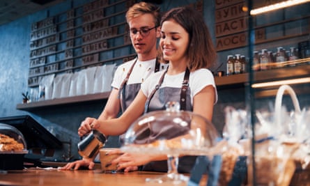 Behind the bar. Two young cafe workers indoors.