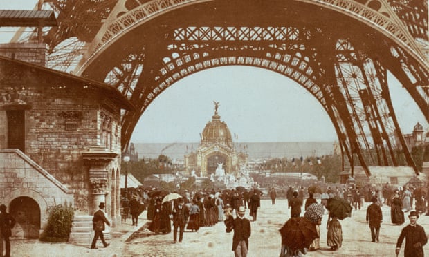 People walk under the Eiffel Tower in 1880s Paris.