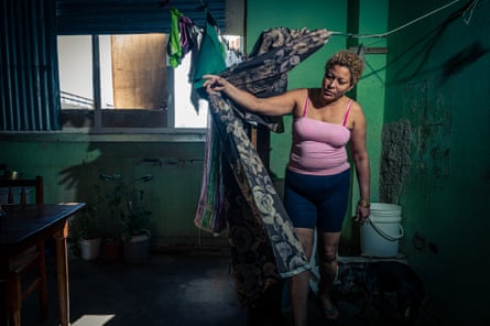 Judit, 51, pulls back the curtain in front of the bath she has built herself in the room where she lives with her daughter Dianela, 18 and son Juan, 12