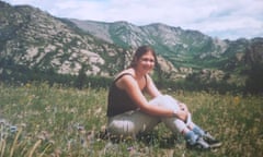 Sarah Brooks sitting on grass with rocky mountains in the background
