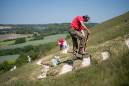 A man uses a spade on a steep hill while rechalking the figure