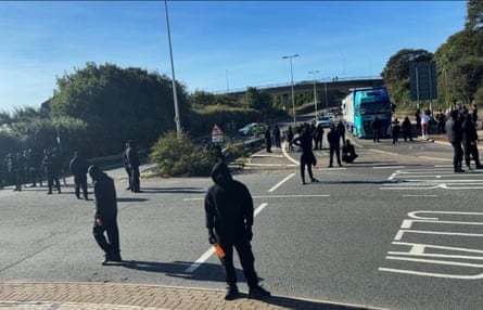 Balaclava-wearing protesters gather earlier today
