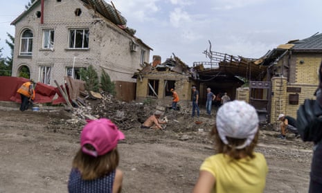 Children watch as workers clean up after a rocket strike on a house in Kramatorsk, Donetsk region, eastern Ukraine, Friday, Aug. 12, 2022.