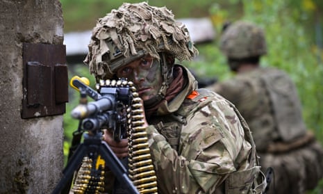 A British soldier in camouflage points a rifle