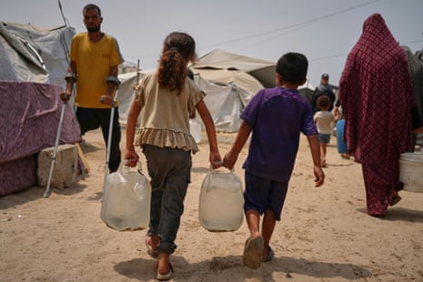 Palestinian children carry jerrycans after collecting water from a distribution point in Gaza City today.