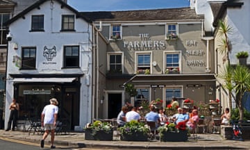 Exterior view of The Farmers pub in Ulverston, UK, on a sunny day with people sitting outside on the pub terrace.