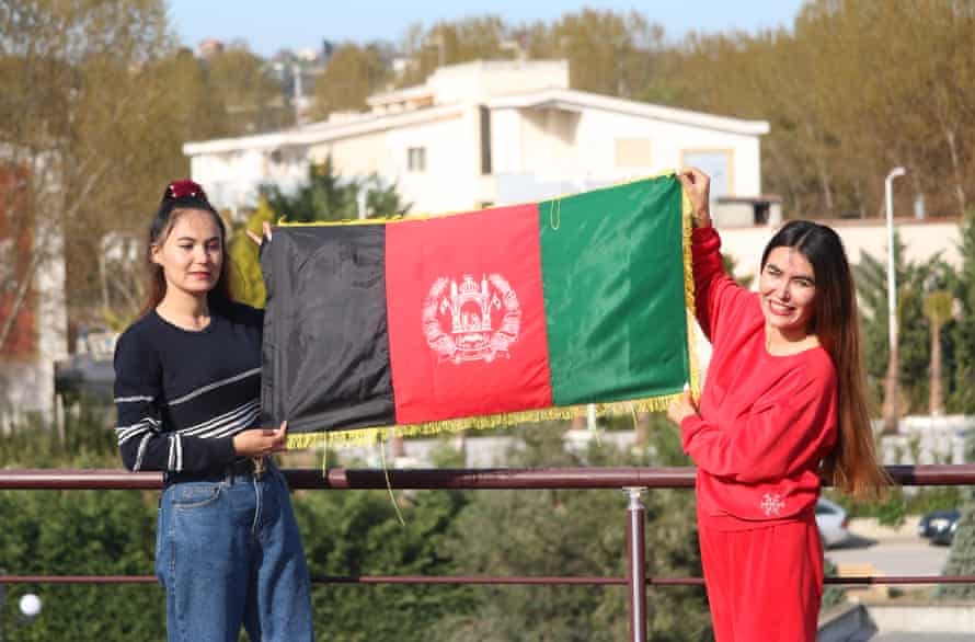 Gulafroz and her sister hold up an Afghanistan flag